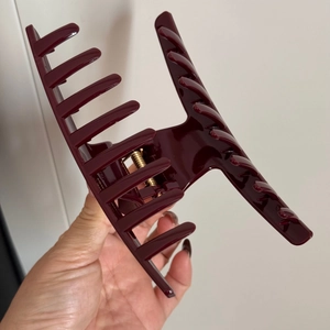 Close-up of a large burgundy hair claw clip with golden spring and glossy finish