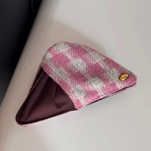 Détail de la texture en tweed rose et plaque dorée gravée love sur le sac en tissu