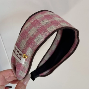 Vue détaillée d'un serre-tête en tweed rose à carreaux avec étiquette et cœur doré