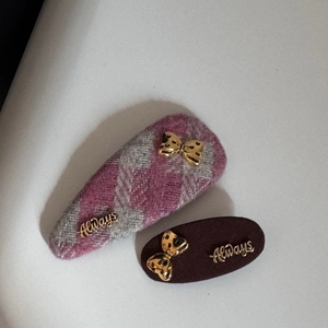 Détail de barrettes en laine à carreaux roses et marron avec nœuds dorés et cœurs évidés