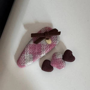 Détail de la pince à cheveux en tweed rose avec nœud marron et pendentif cœur