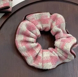 Détail d'un chouchou pied-de-poule rose avec bordure brune sur plateau en bois