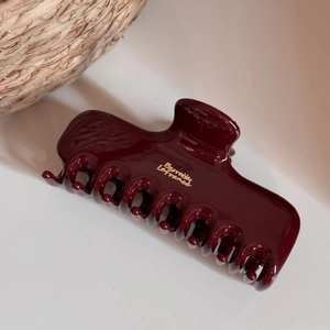 Macro detail of glossy dark red hair claw clip with gold Barrette La France text