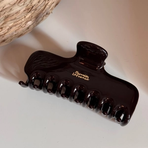 Detailed macro view of glossy dark brown hair claw clip with gold Barrette La France text