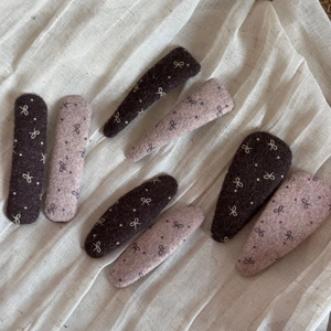 Detailed macro view of wool felt hair clips in coffee and pink with bow pattern