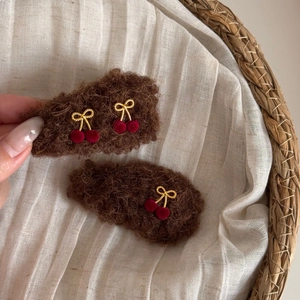 Detail of plush cherry bow hair clips in dark brown teddy fur fabric for winter hair styling
