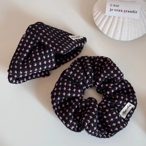 Close-up of pink and black knit scrunchie with a handmade label on white tray