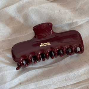 Detailed close-up of dark red French style hair claw clip with gold lettering on soft fabric