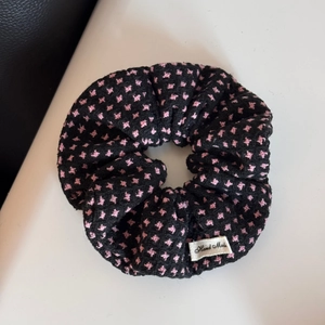 Detail view of black polka dot scrunchie with pink stars and Hand Made label