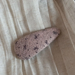 Detail of tear-drop BB hair clip with wool felt texture and black bow pattern