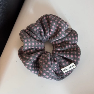 Close-up of French-style grey polka dot scrunchie with a Hand Made woven label