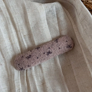 Close-up of grey pink felt hair clip with black bow and polka dots on linen fabric