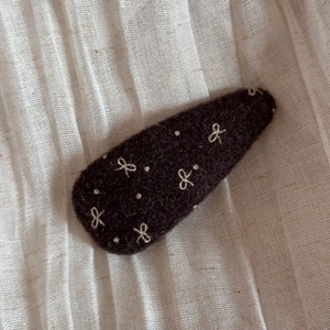 Close-up of wool fabric BB clip featuring white embroidered bow and polka dots pattern