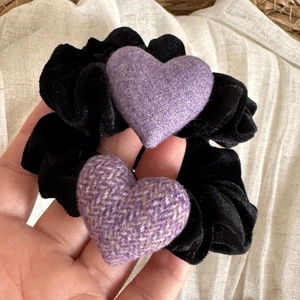 Gros plan détaillé des cœurs en tissu violet sur chouchous en velours noir texture tweed