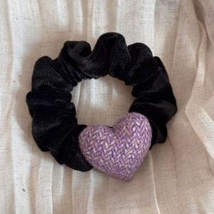 Détail d'un chouchou en velours noir orné d'un cœur en tweed violet et texturé