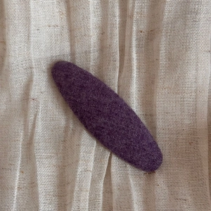 Détail macro d'une pince à cheveux en tissu violet avec texture tissée sur lin beige