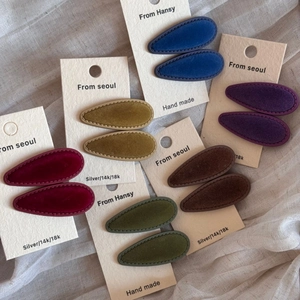 Detail view of colorful velvet teardrop hair clips on branded cream display cards