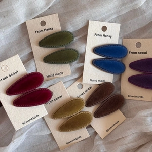 Detail view of multi-color vintage velvet teardrop hair clips on white fabric
