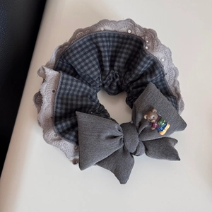 Detailed view of lace trim hair scrunchie with grey checkered bow and cute bear ornament