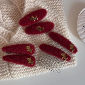 Elegant red wool hair clips set with gold horse charms on soft white fabric background