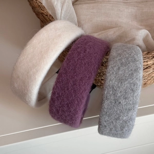 Close-up of three wide wool hairbands in beige, purple, and grey with a soft fuzzy texture
