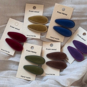 Detail of multi-color velvet waterdrop hair clips on branded card with premium texture