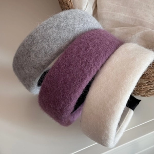 Close-up of wide wool fabric headbands in grey, purple, and cream with plush texture
