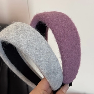 Close-up showing the fluffy wool texture of thick grey and purple headbands