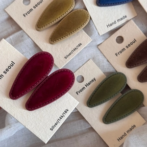 Detailed macro view of handmade velvet teardrop hair clips in various vintage colors
