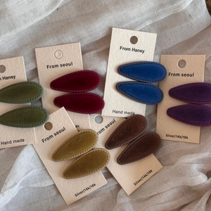 Close-up of velvet teardrop hair clips in multiple colors on a branded display card