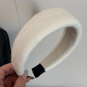 Detailed view of plush white padded headband with soft wool texture and black fabric tips