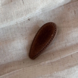 Detailed view of vintage dark brown velvet hair clip with premium stitching on linen background