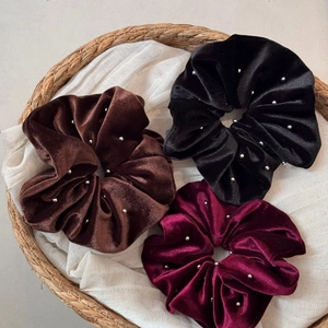 Close-up of velvet scrunchies with silver beads in brown, black and wine red colors