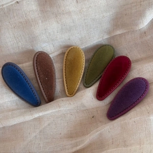 Detailed view of six vintage teardrop hair clips in velvet textures with stitch edges
