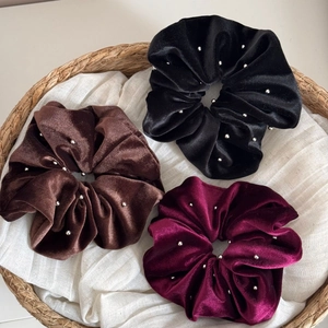 Three velvet scrunchies in black, brown, and wine red with sparkling silver beads set in basket