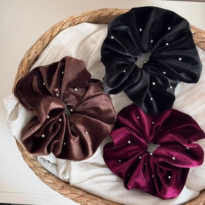 Close-up of three large velvet hair scrunchies in black, brown and burgundy with small silver beads