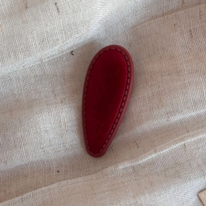 Macro view of vintage wine red velvet waterdrop hair clip with detailed stitching textures