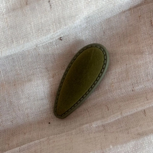 Detail of dark green velvet waterdrop hair clip with elegant stitched edge texture
