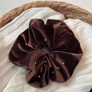 Close-up of brown velvet scrunchie with silver bead studs on textured linen cloth