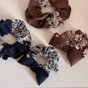 Detail of four vintage knit scrunchies in brown and navy blue with floral embroidery and bows