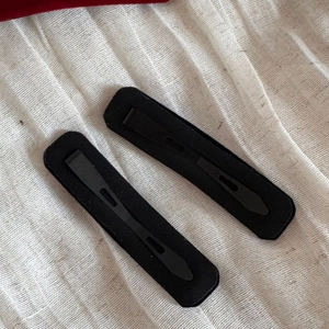 Detail view showing the back of two black velvet hair clips with metal snap fastener mechanisms
