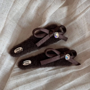 Detail of dark brown plush hair clip with ribbon bow, rhinestone and handmade tag
