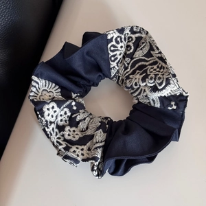 Detailed view of large navy blue scrunchie with white floral embroidery for hair