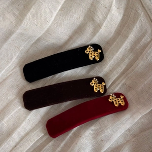 Detailed macro view of velvet hair clips with golden poodle accents in black, coffee, and wine red