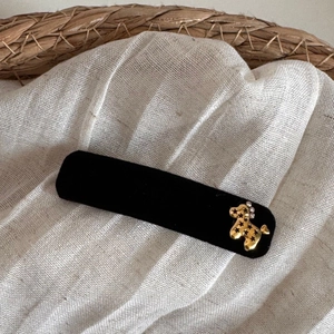 Close-up of black velvet hair clip with golden poodle charm and sparkling rhinestones