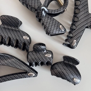Macro detail of carbon fiber texture hair clips with silver handmade metal tags
