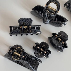 Detail of carbon fiber texture hair claw clips with gold spring and handmade metal tag