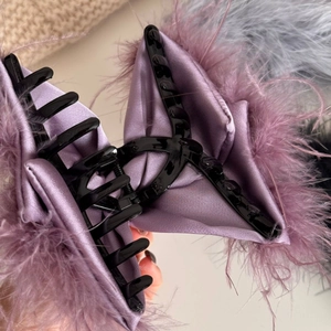 Macro detail of elegant purple feather hair claw clip with silk satin fabric wrapping