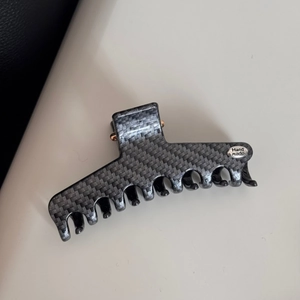 Detail of silver-grey carbon fiber pattern hair claw clip with silver Hand Made plaque