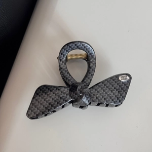 Detail showing faux carbon fiber weave texture and gold metal spring on the bow hair claw